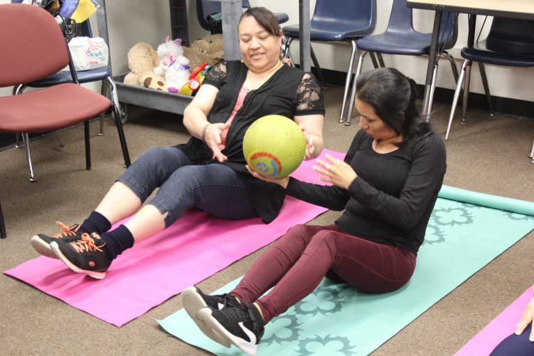 Two women on exercise mats working their core muscles.