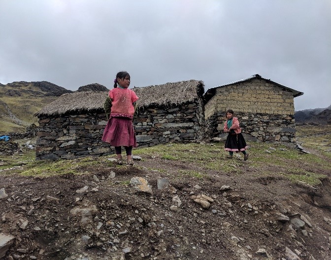 A group of children standing in a dirt field Description automatically generated